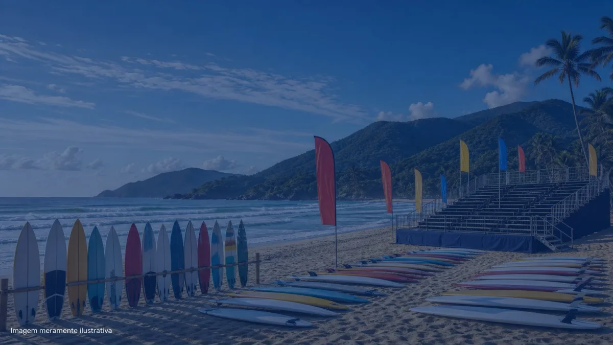 Pranchas de surf alinhadas na areia ao lado de bandeiras de competicao, imagem meramente ilustrativa