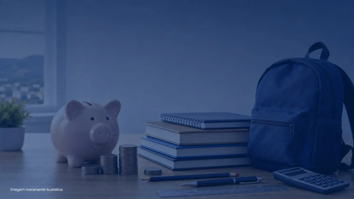Cofrinho ao lado de livros escolares, caderno e mochila sobre mesa de estudo, imagem meramente ilustrativa