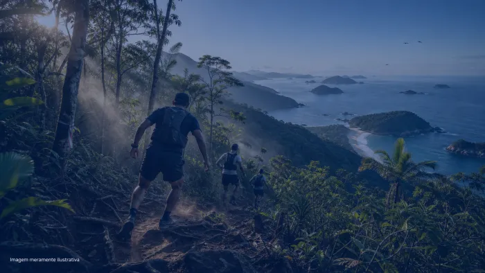 Corredores de trail run descendo trilha de mata atlântica com o mar ao fundo, imagem meramente ilustrativa