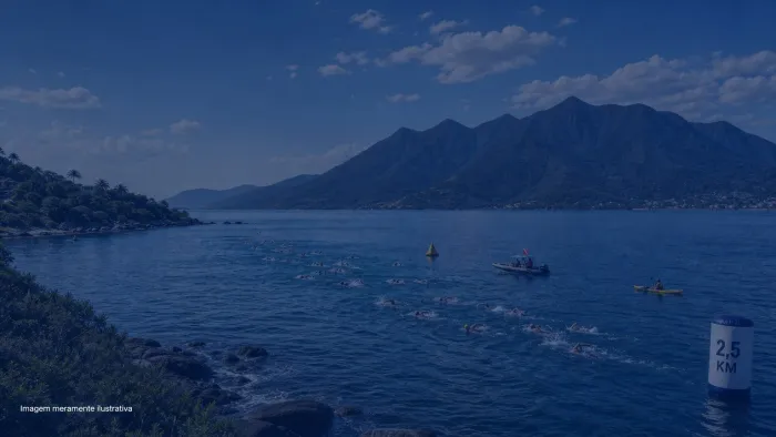 Nadadores em aguas abertas durante travessia com barco de apoio e ilha montanhosa ao fundo, imagem meramente ilustrativa