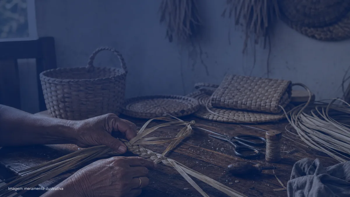 Mãos de artesã trançando fibras naturais de taboa sobre uma mesa de madeira, imagem meramente ilustrativa