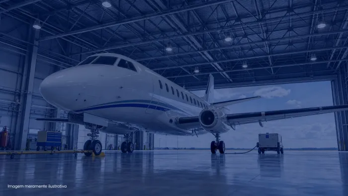 Aviao comercial de pequeno porte estacionado em hangar iluminado, imagem meramente ilustrativa