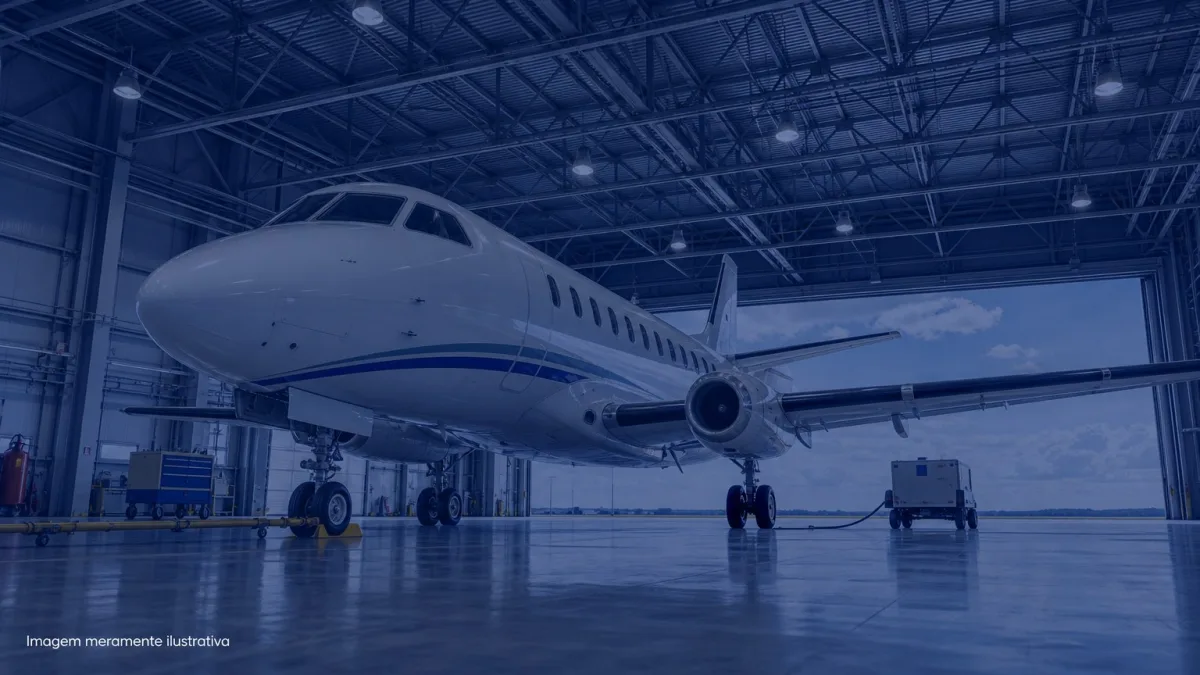 Aviao comercial de pequeno porte estacionado em hangar iluminado, imagem meramente ilustrativa
